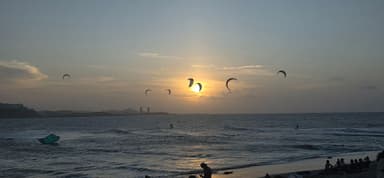 A sunset over the ocean with kitesurfers in the foreground.