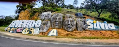 Un grand panneau sculpté avec des visages et des mots colorés sur une colline.