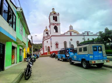 Une rue avec des bâtiments colorés et une église au fond sous un ciel nuageux.