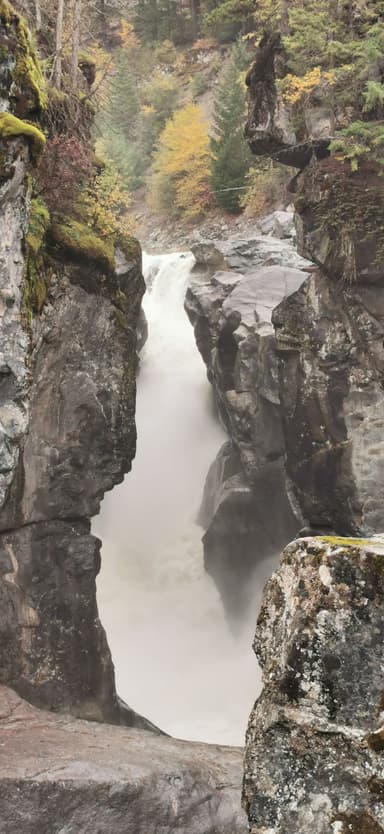 Une cascade majestueuse entourée de rochers et d'arbres d'automne.