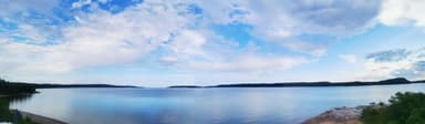 Un paysage paisible avec un lac et des nuages dans le ciel.