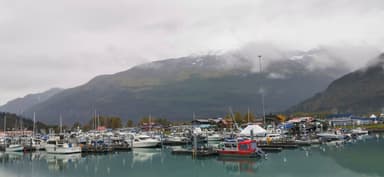 Un port avec des bateaux et des montagnes en arrière-plan sous un ciel nuageux.