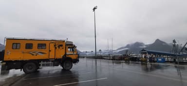 Un camion jaune stationné près d'un port sous un ciel nuageux.