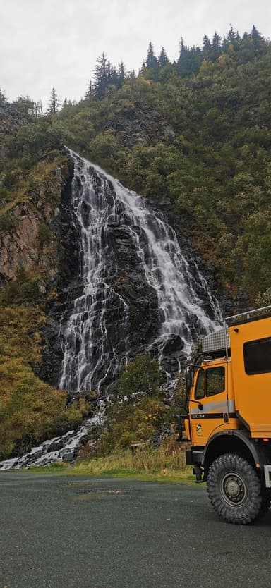 Une cascade majestueuse avec un camion orange à proximité.