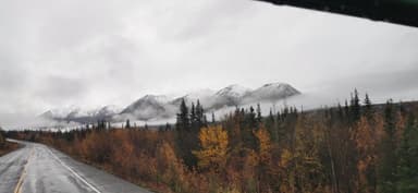 Des montagnes enneigées avec des arbres colorés au premier plan.