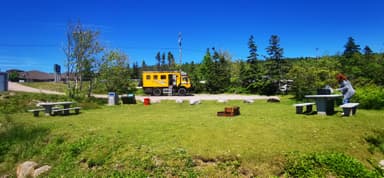 Un paysage verdoyant avec un camion jaune et des tables de pique-nique.