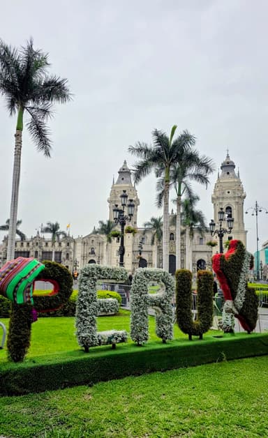 Un jardin avec des lettres formant 'PERU' et un bâtiment en arrière-plan.