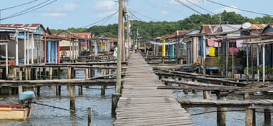 Un chemin en bois entre des maisons colorées au bord de l'eau.