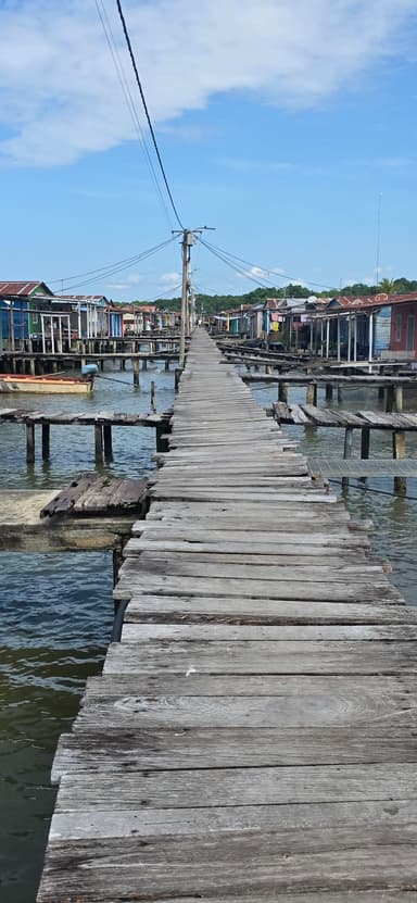 Un pont en bois menant à des maisons colorées au bord de l'eau.