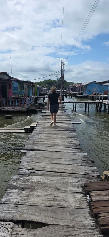 Un homme marche sur un pont en bois au-dessus de l'eau.
