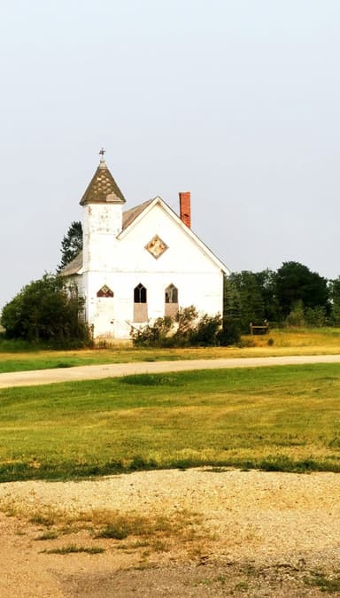 Une vieille église blanche dans un champ verdoyant.
