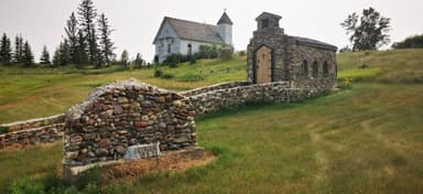 Une église en bois et un petit bâtiment en pierre dans un champ verdoyant.