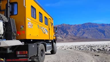 Un camion jaune sur un chemin dans le désert de Death Valley sous un ciel bleu.
