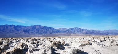 Un paysage désertique avec des montagnes au loin sous un ciel bleu.