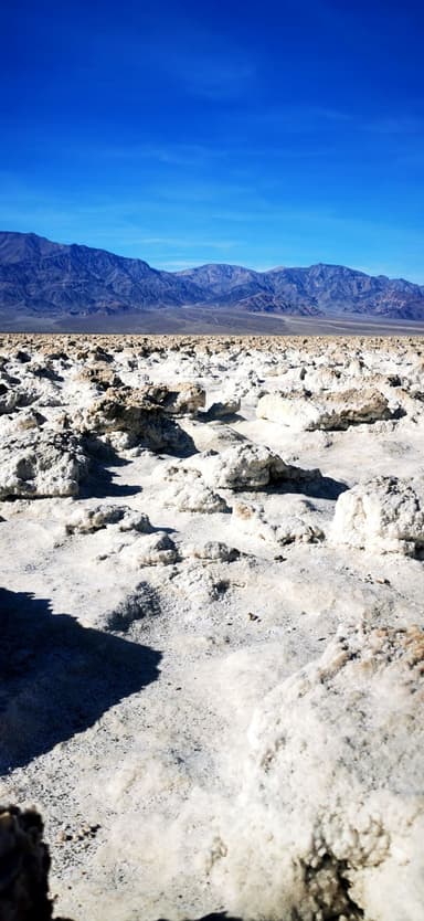 Un paysage désertique avec des formations rocheuses et des montagnes au loin.