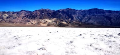 Un paysage désertique avec des montagnes en arrière-plan sous un ciel bleu.