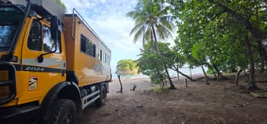Un véhicule jaune près d'une plage entourée de palmiers.