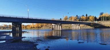 Un pont au-dessus d'une rivière avec des arbres d'automne en arrière-plan.