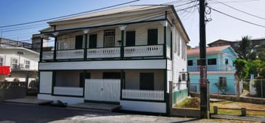 Une maison coloniale blanche avec balcons à Cayo, Belize, sous un ciel bleu.