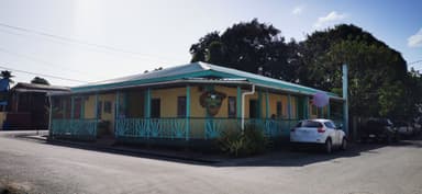 Un bâtiment coloré avec un porche et des voitures garées à Cayo.