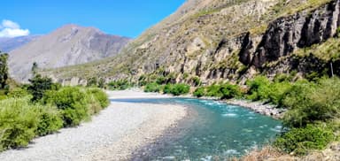 Une rivière serpentant entre des collines verdoyantes sous un ciel bleu.