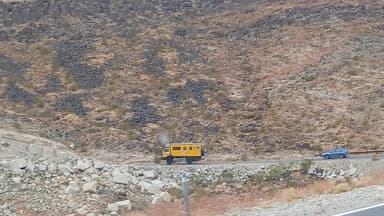 Un véhicule jaune sur une route de montagne.