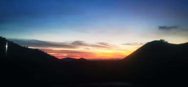 Un coucher de soleil sur des collines sombres.