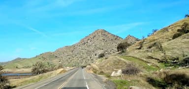 Une route menant à des collines sous un ciel bleu.