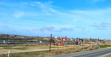 Un paysage industriel avec des pompes à pétrole sous un ciel bleu.