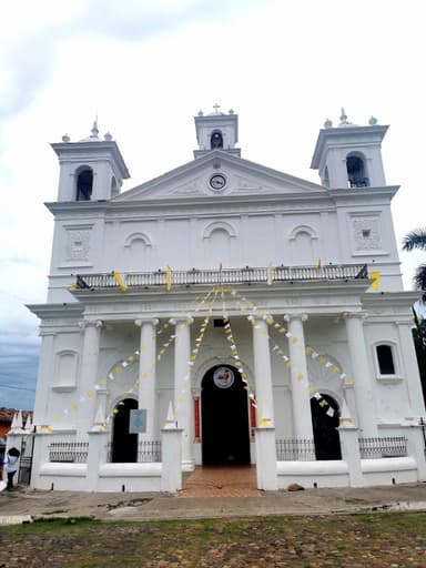 Une église blanche avec des décorations et un ciel nuageux.
