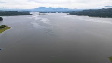 Un paysage de lac avec des montagnes en arrière-plan sous un ciel nuageux.