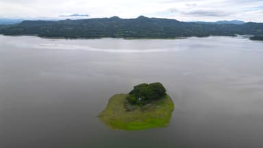 Une vue aérienne d'une petite île dans un lac entourée de montagnes verdoyantes.