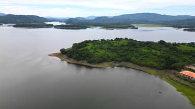 Un paysage de lac entouré de collines verdoyantes sous un ciel nuageux.