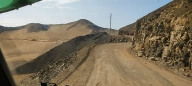 Un chemin sinueux à travers des collines désertiques sous un ciel clair.