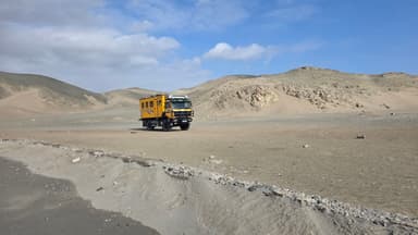 Un camion jaune sur un paysage désertique à Huacho, avec des collines en arrière-plan.