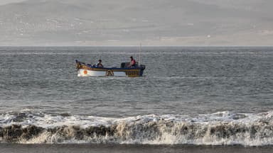 Un bateau de pêche sur l'océan avec des vagues au premier plan.