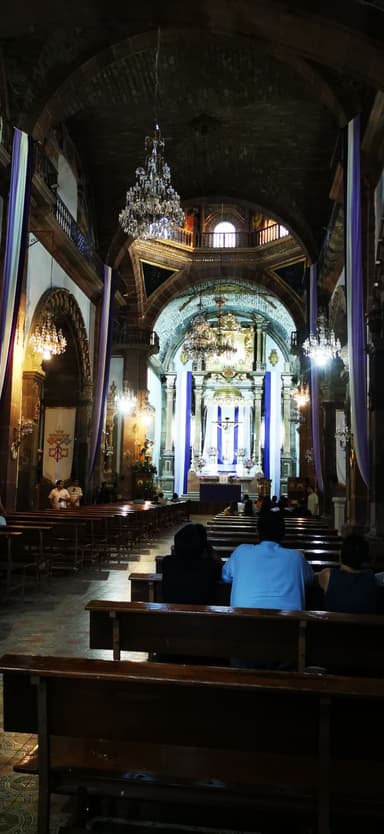 Intérieur d'une église avec des bancs et des chandeliers.