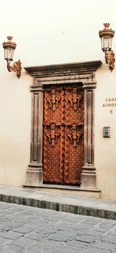 Une porte en bois sculpté avec des lanternes sur les côtés.
