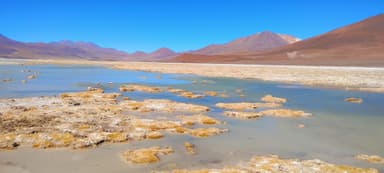 Un paysage naturel avec des formations rocheuses et un lac sous un ciel bleu.
