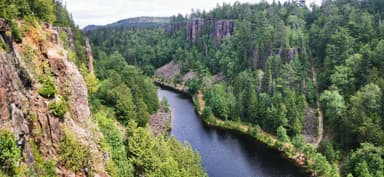 Une vue panoramique d'une rivière entourée de falaises et de forêts verdoyantes.