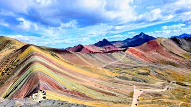 Un paysage coloré de montagnes à Cusipata, sous un ciel nuageux.