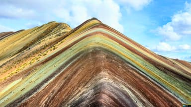 Une montagne colorée avec des strates visibles sous un ciel bleu.