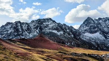 Un paysage montagneux avec des sommets enneigés et des nuages.
