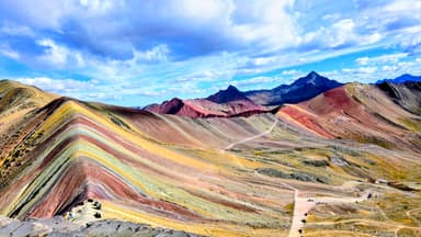 Un paysage coloré de montagnes à Cusipata, sous un ciel nuageux.