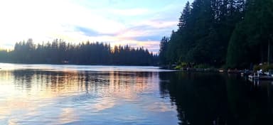 Un lac tranquille au coucher du soleil avec des arbres en arrière-plan.