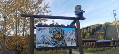 Un panneau d'accueil du Troll Resort avec des montagnes en arrière-plan.