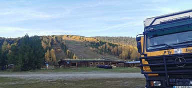 Un paysage de montagne avec un camion et des bâtiments en arrière-plan.