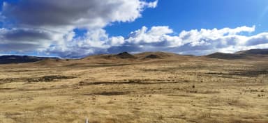 Un paysage de collines et de nuages au-dessus d'une prairie.