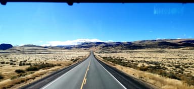 Une route s'étend à travers un paysage désertique sous un ciel bleu.