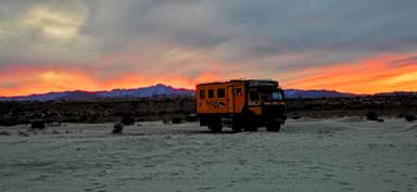 Un camion orange sur un paysage désertique au coucher du soleil.